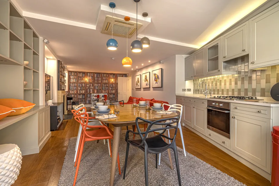 Real estate photograph of a contemporary dining area with wooden table, colourful chairs and decorative shelving in London