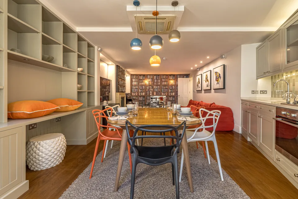 Real estate photograph of a modern dining room featuring a wooden table, colourful chairs and a designer lamp in London