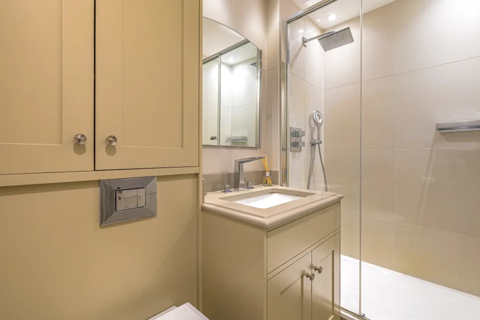 Real estate photograph of a modern bathroom with glass shower, stylish sink and illuminated mirrors in London