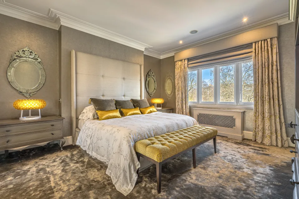 Real estate photograph of a stylish bedroom with a padded headboard, double bed and golden lamps in London