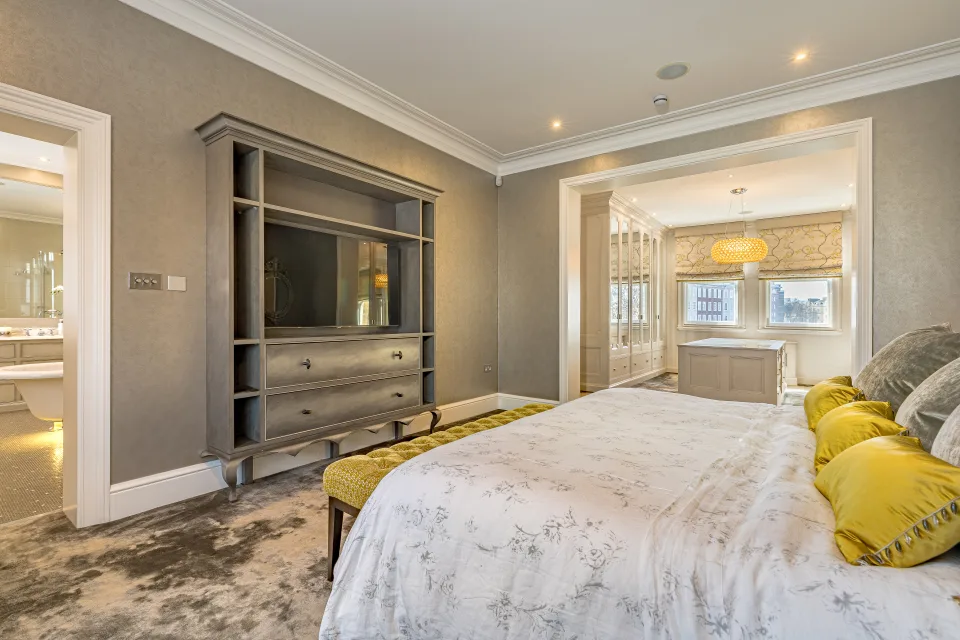 Real estate photograph of a bright bedroom featuring a large bed, stylish wardrobe and modern decor in London