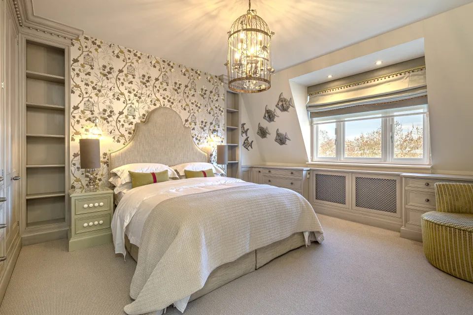 Real estate photograph of an elegant bedroom with floral wallpaper, a large bed and decorative lighting in London
