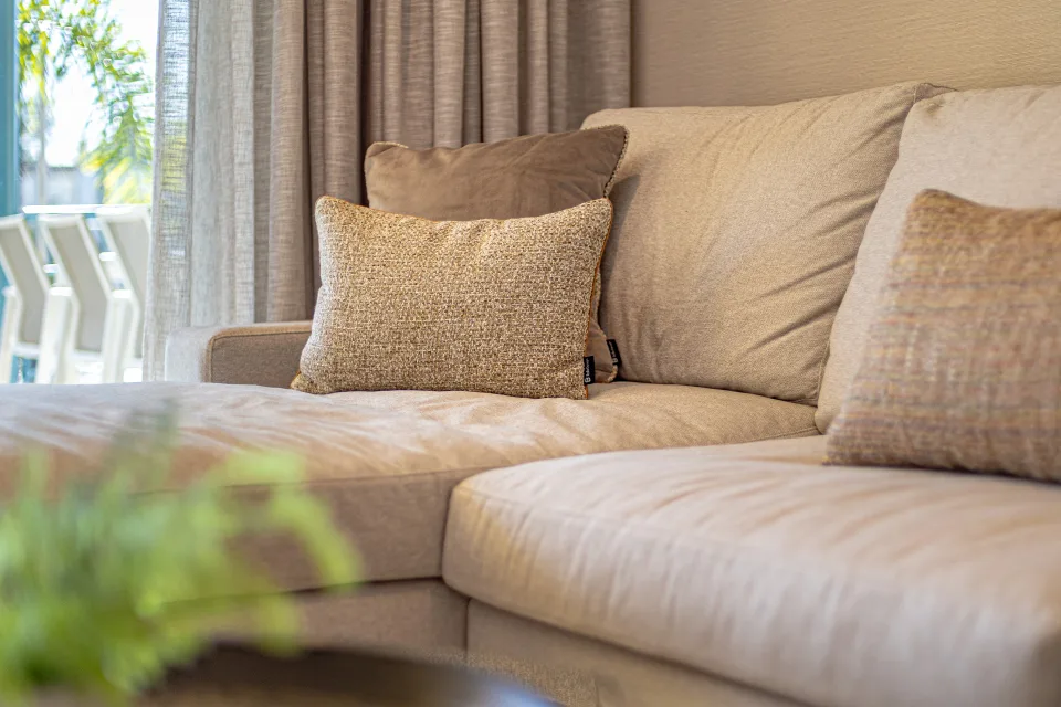 Fotografía de interiorismo y arquitectura de un acogedor sofá beige con cojines texturizados y cortinas suaves en Sotogrande