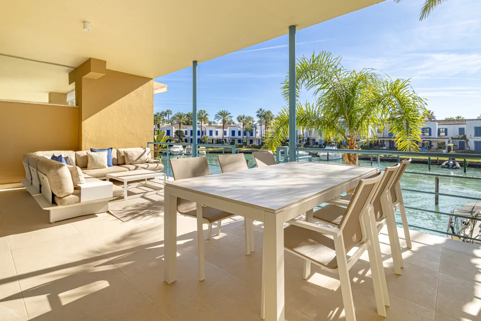 Fotografía de interiorismo y arquitectura de una amplia terraza con mesa de comedor blanca, sillas modernas en Sotogrande