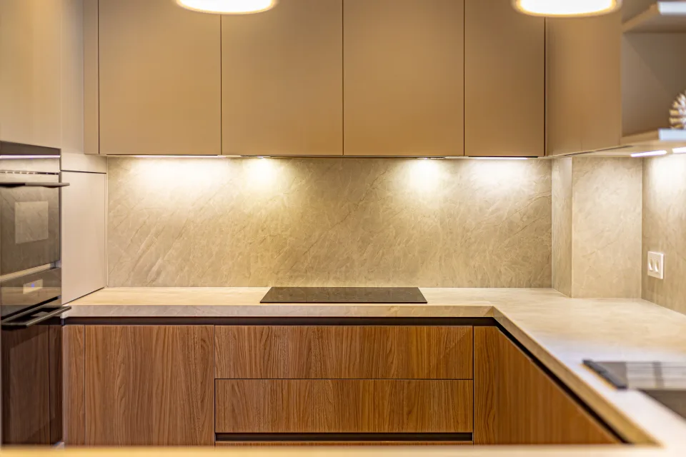 Fotografía de interiorismo y arquitectura de una cocina moderna con armarios de madera, encimera clara y luz suave en Sotogrande