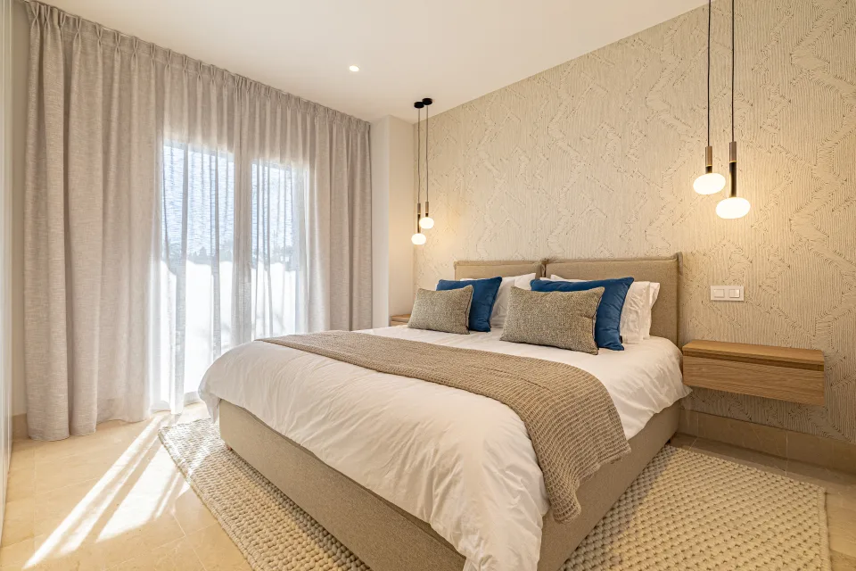 Fotografía de interiorismo y arquitectura de un dormitorio acogedor con cama grande, cabecero tapizado, sábanas claras en Sotogrande