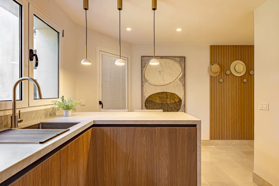 Interior design and architecture photograph of a modern kitchen with wooden bars, pendant lights, and decorative wall features in Sotogrande