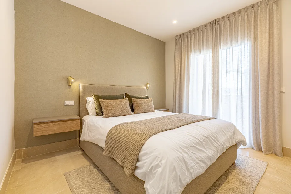 Interior design and architecture photograph of an elegant bedroom featuring a large bed, upholstered headboard in Sotogrande